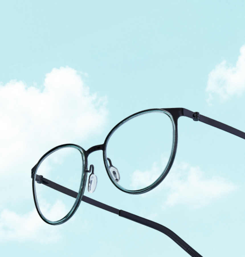 Round black eyeglasses float in front of a blue sky with white clouds